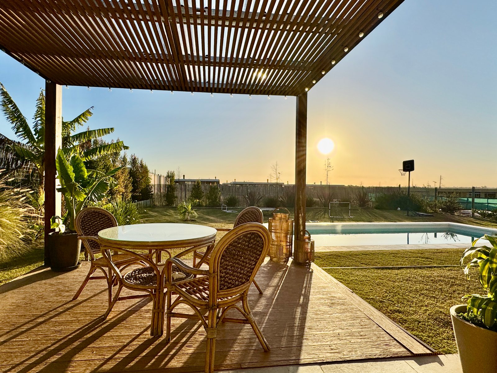 Pérgola con deck y piscina al atardecer