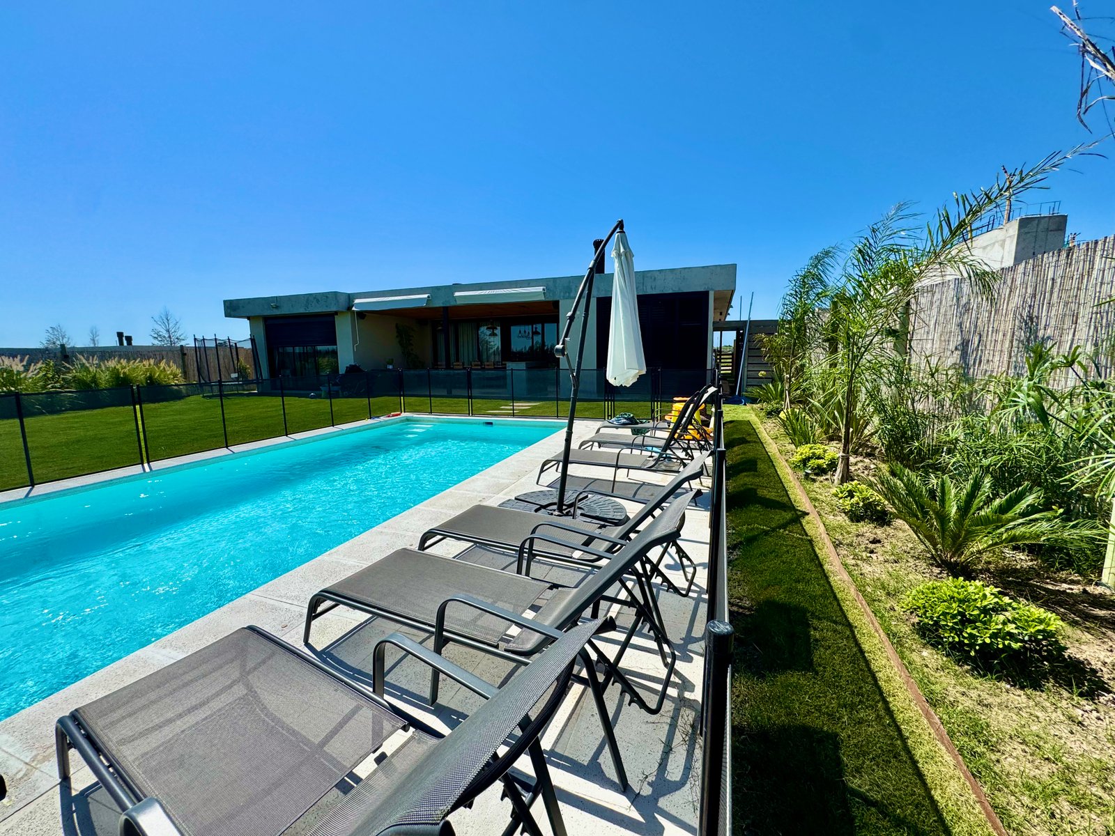 Piscina con reposeras y jardín